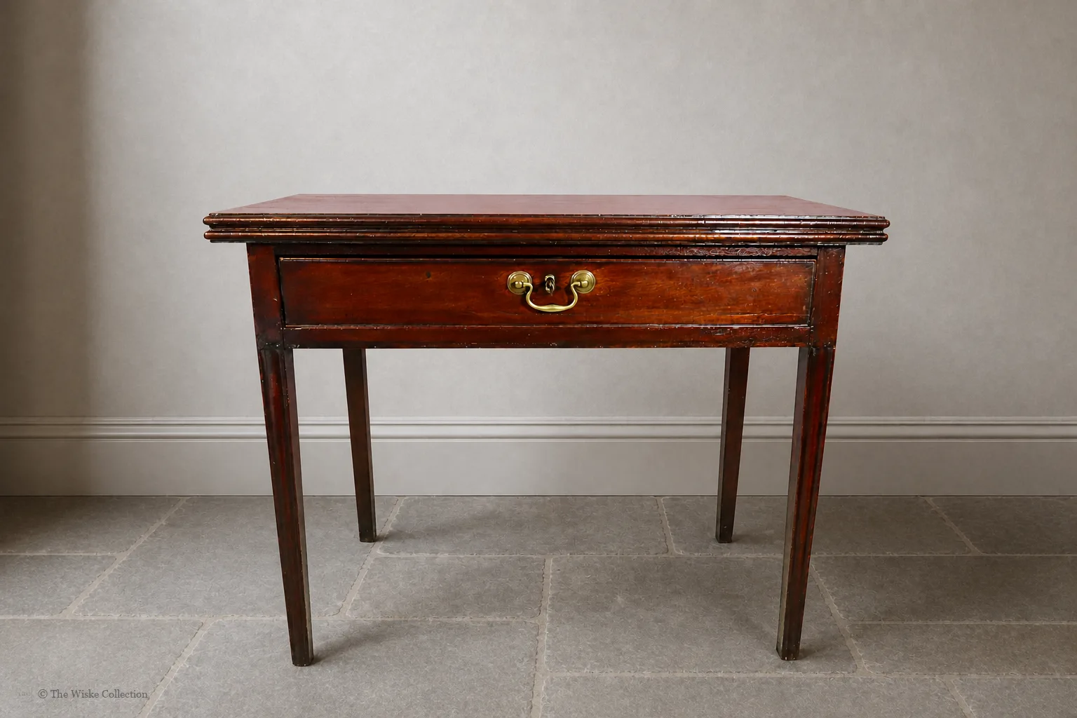 Georgian mahogany turnover-top tea table; rectangular hinged leaf unfolds to a square surface; single frieze drawer with brass swan-neck handle and escutcheon; square tapering legs