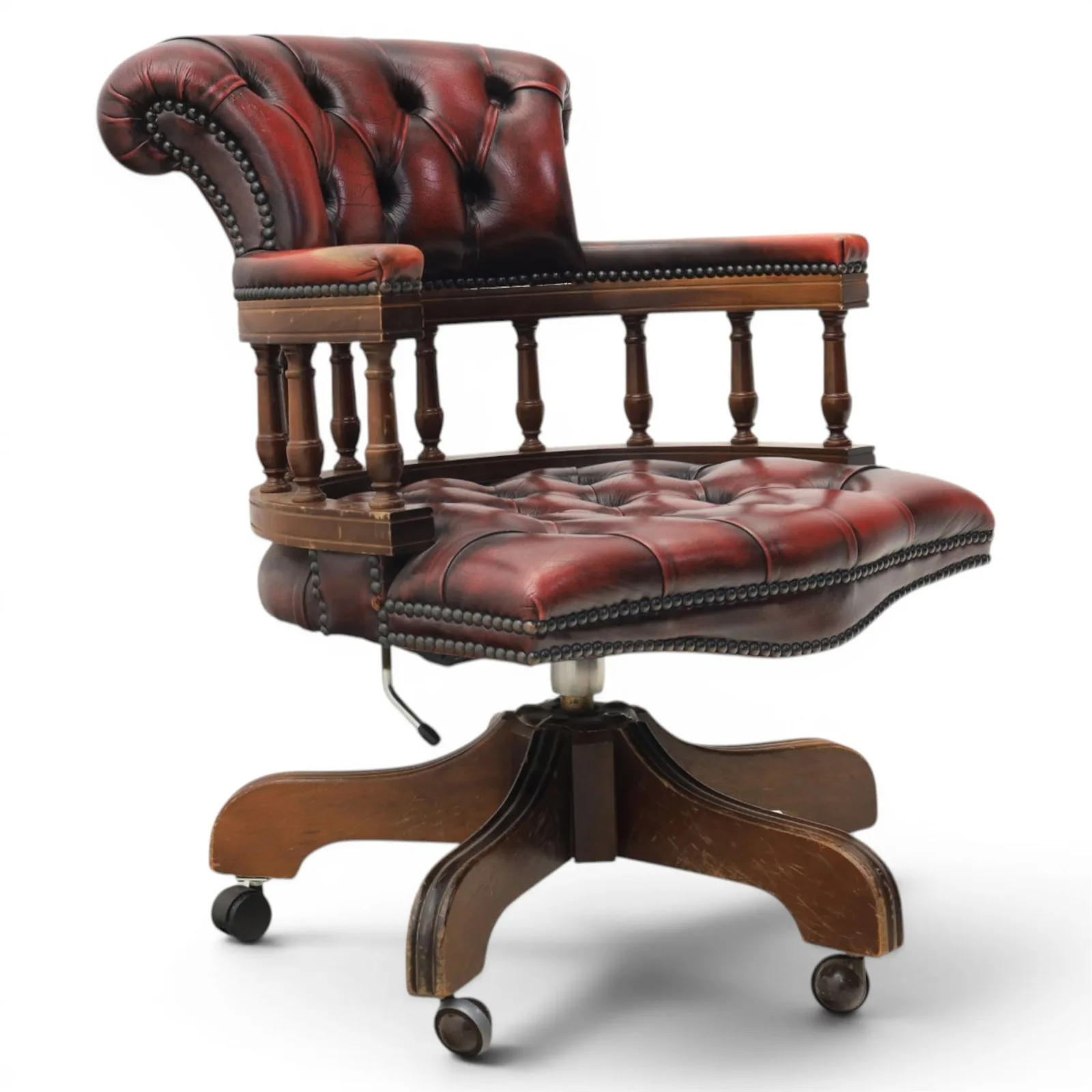 Captains swivel desk chair upholstered in oxblood leather, buttoned back and seat, shaped arm bow raised on turned spindles, five spoke base raised on castors - Plate 1